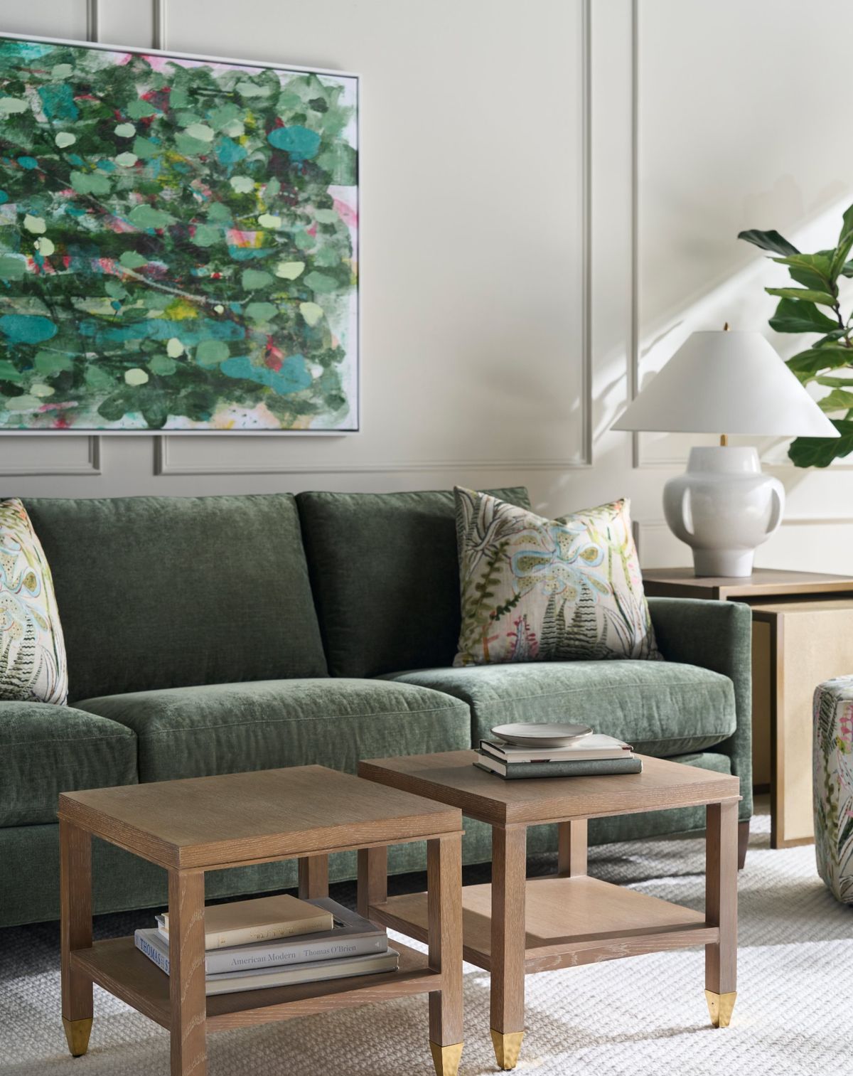 Green velvet sofa with abstract art and brass-capped side tables
