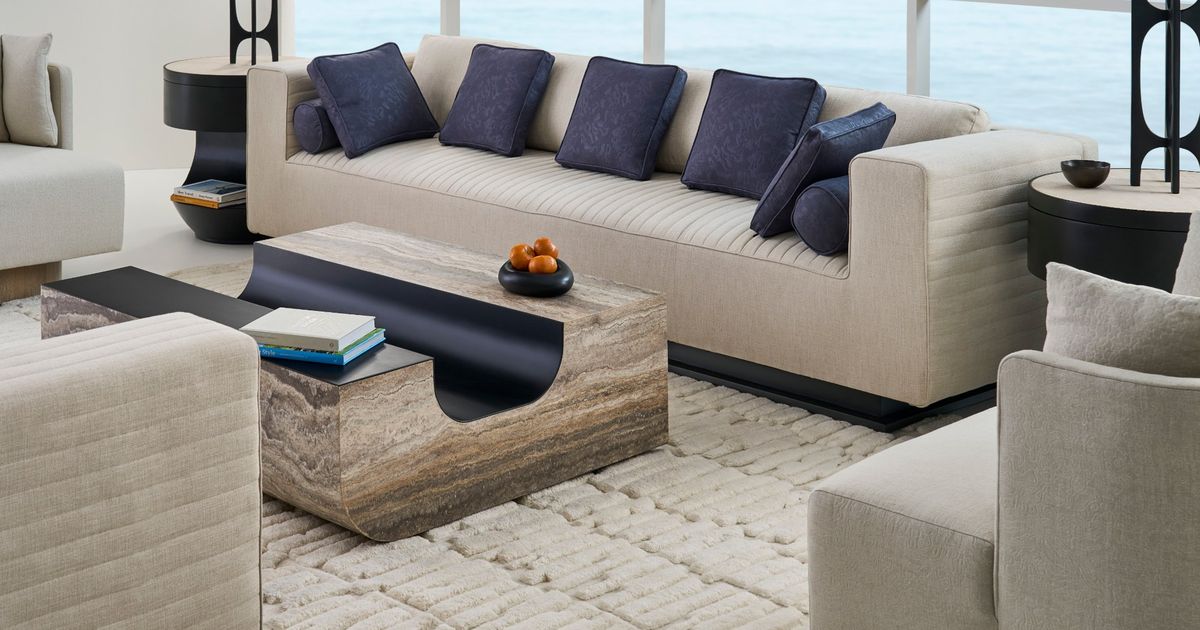Channel-tufted ivory sofa with navy pillows and a travertine table